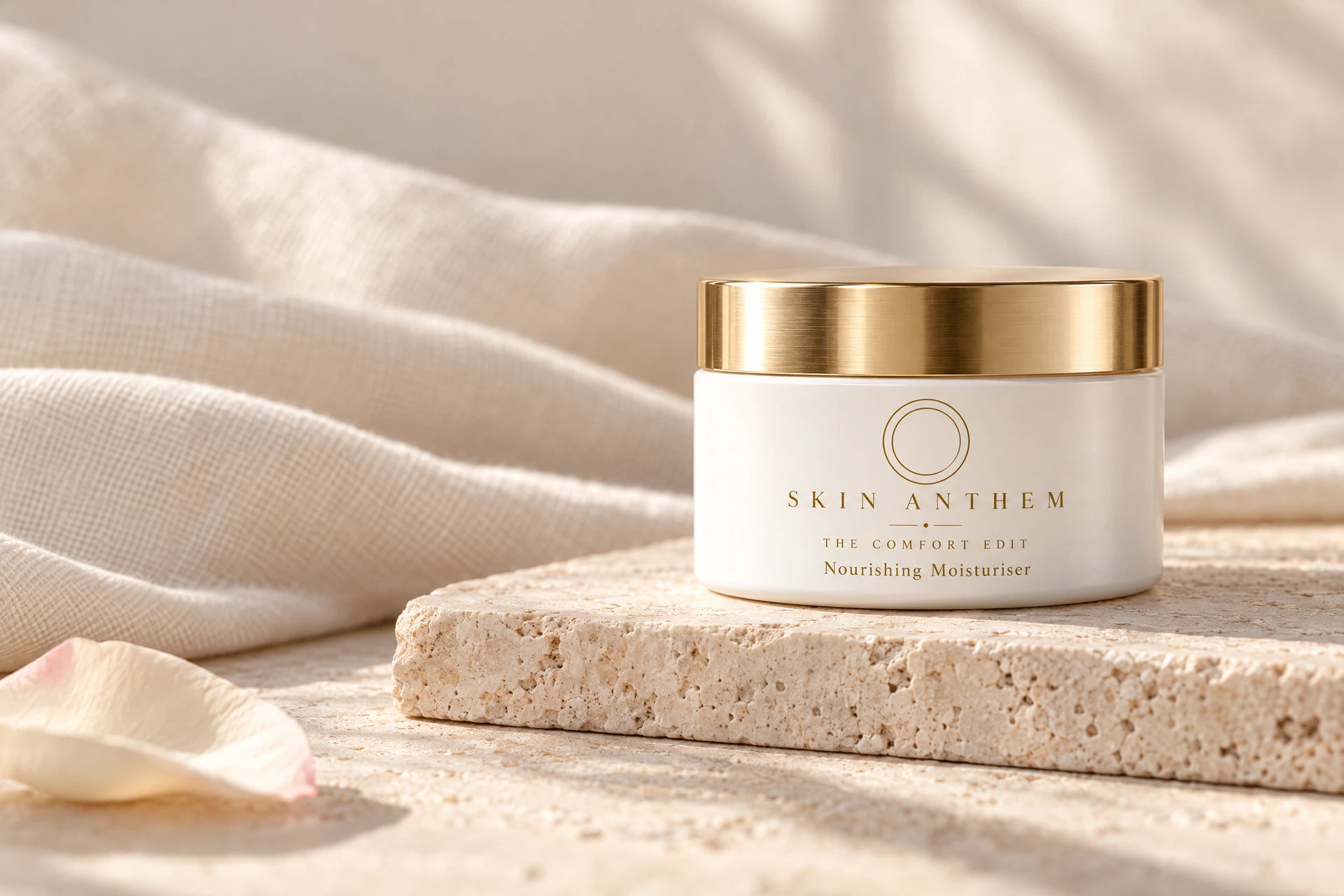 White moisturiser jar with gold lid on stone.