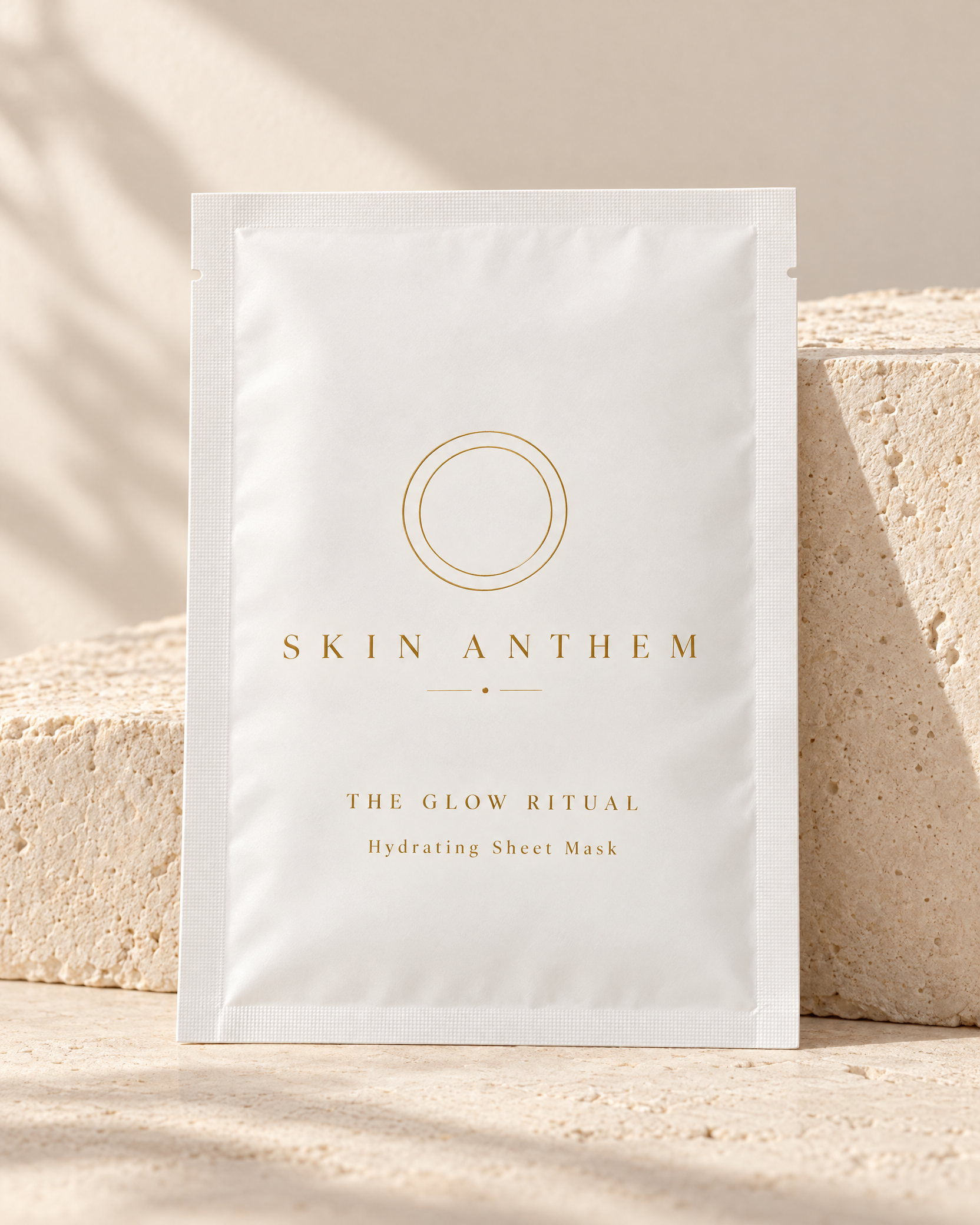 White sheet-mask sachet against pale stone blocks.